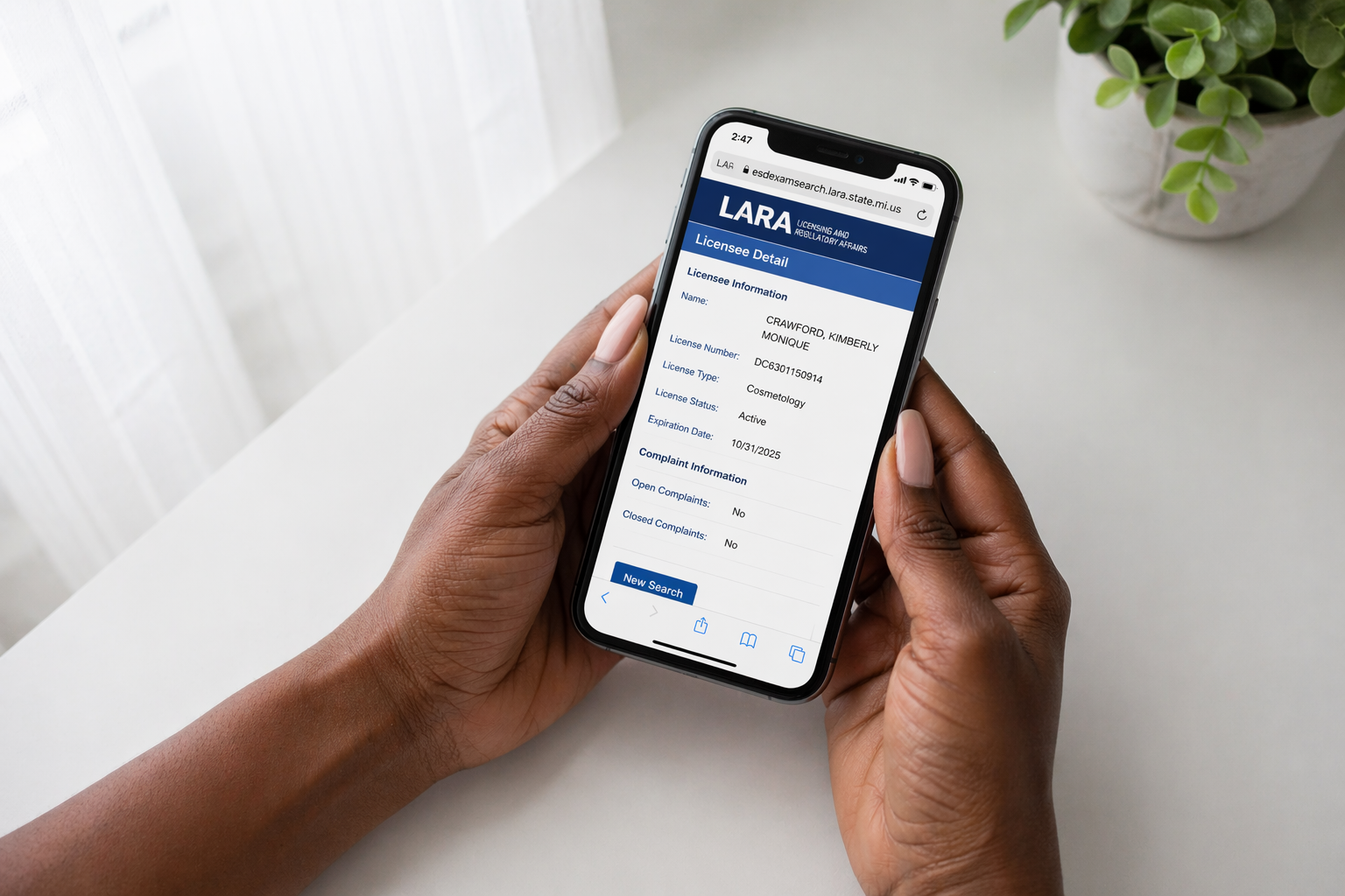 Hands holding a smartphone showing the Michigan LARA license lookup portal used to verify a Botox provider's credentials