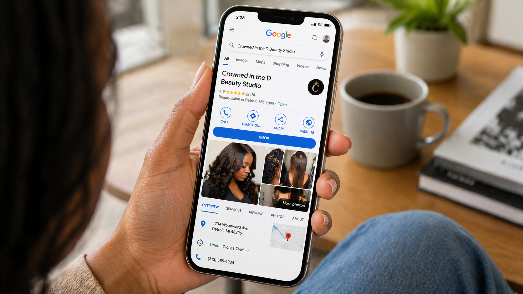 Busy modern Detroit hair salon interior with a Black female stylist working on a client’s natural hair, warm lighting and professional styling stations
