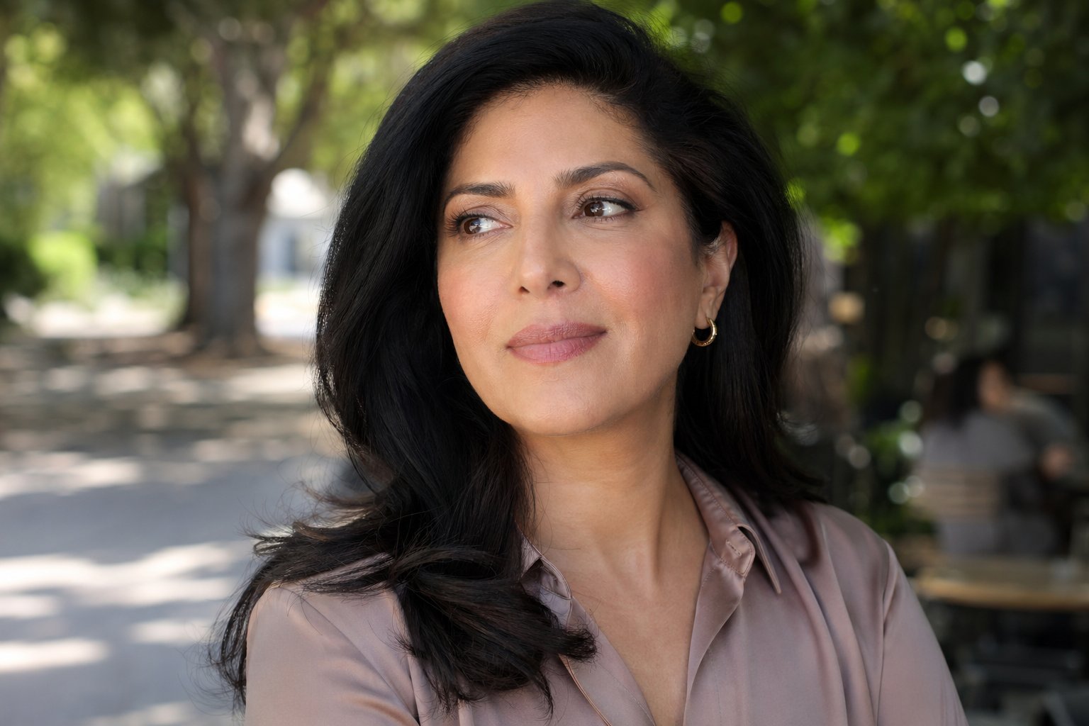 Arab-American woman in her late 40s standing outdoors in natural light, glowing clear skin, calm and confident expression — post-treatment radiance