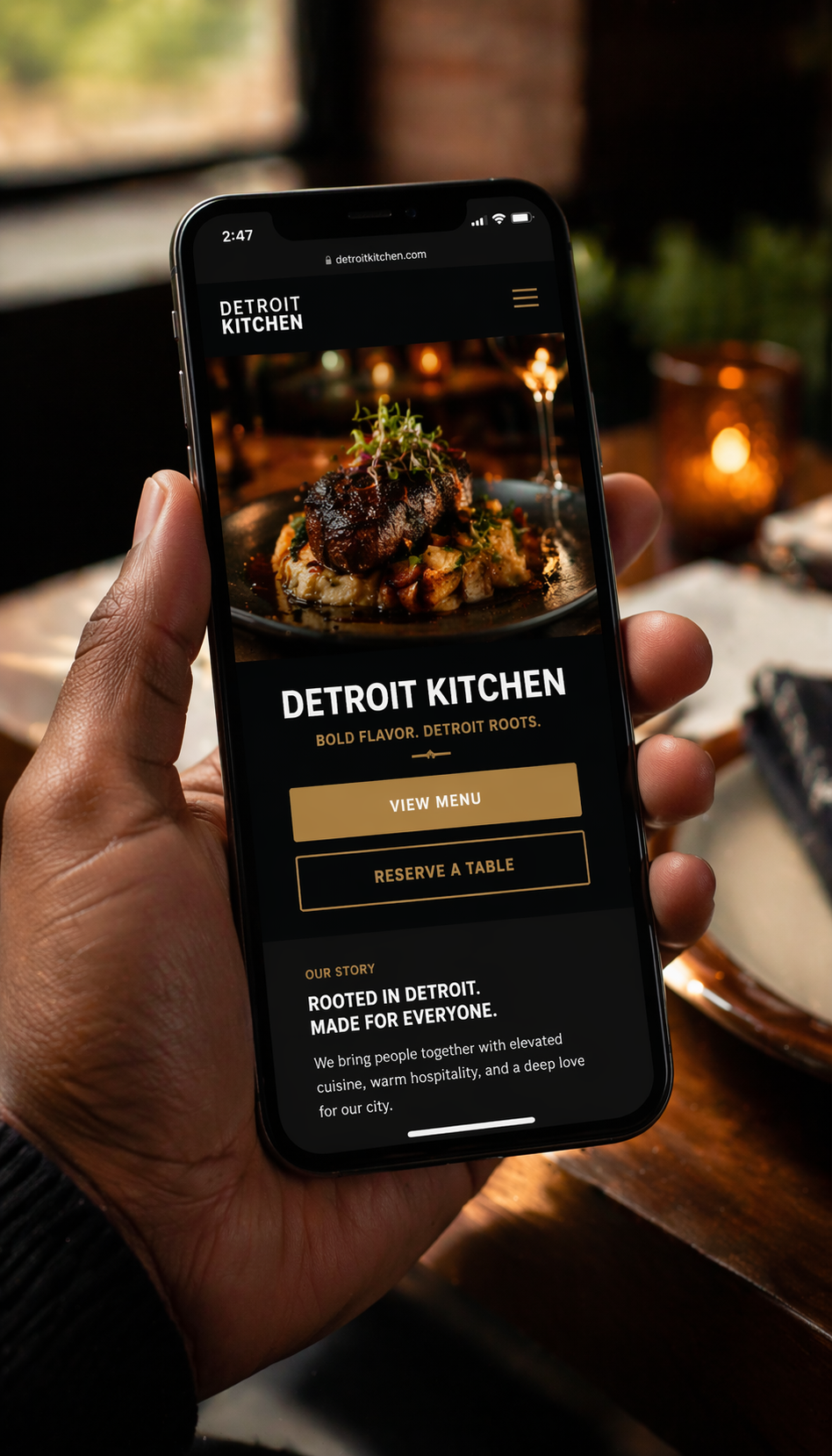 Hand holding iPhone displaying a modern restaurant website with menu and reserve a table button